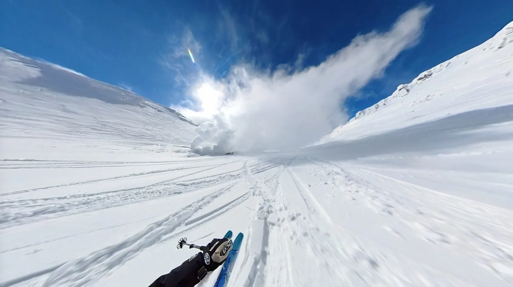 A first-person view skiing down a snow gully on Asahidake straight toward a large white plume of volcanic steam venting from the slope.